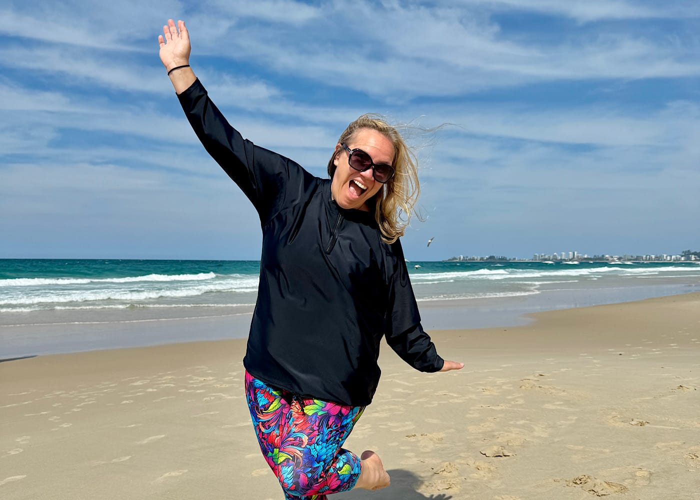 Tanya, founder of OceanRoad Swimwear, smiling confidently on the beach wearing her swimwear design.